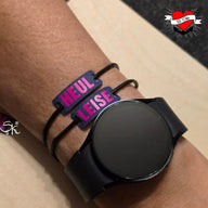 Armband mit personalisierten Schildern "HEUL" und "LEISE" auf einem Handgelenk, zusammen mit einer Smartwatch. Entdecke die "Armband und Schnürsenkel Schilder mit Wörtern" Plotter und Laser Datei von easy-sticks für kreative Projekte.