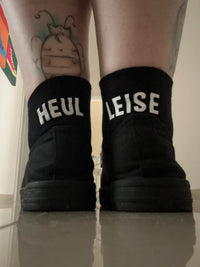 Schwarze Sneakers mit den Aufschriften 'HEUL' und 'LEISE', kombiniert mit einem verspielt gezeichneten Tattoo. Ein cooles Beispiel für die Kreativität aus der Plotter und Laser Datei von easy-sticks.