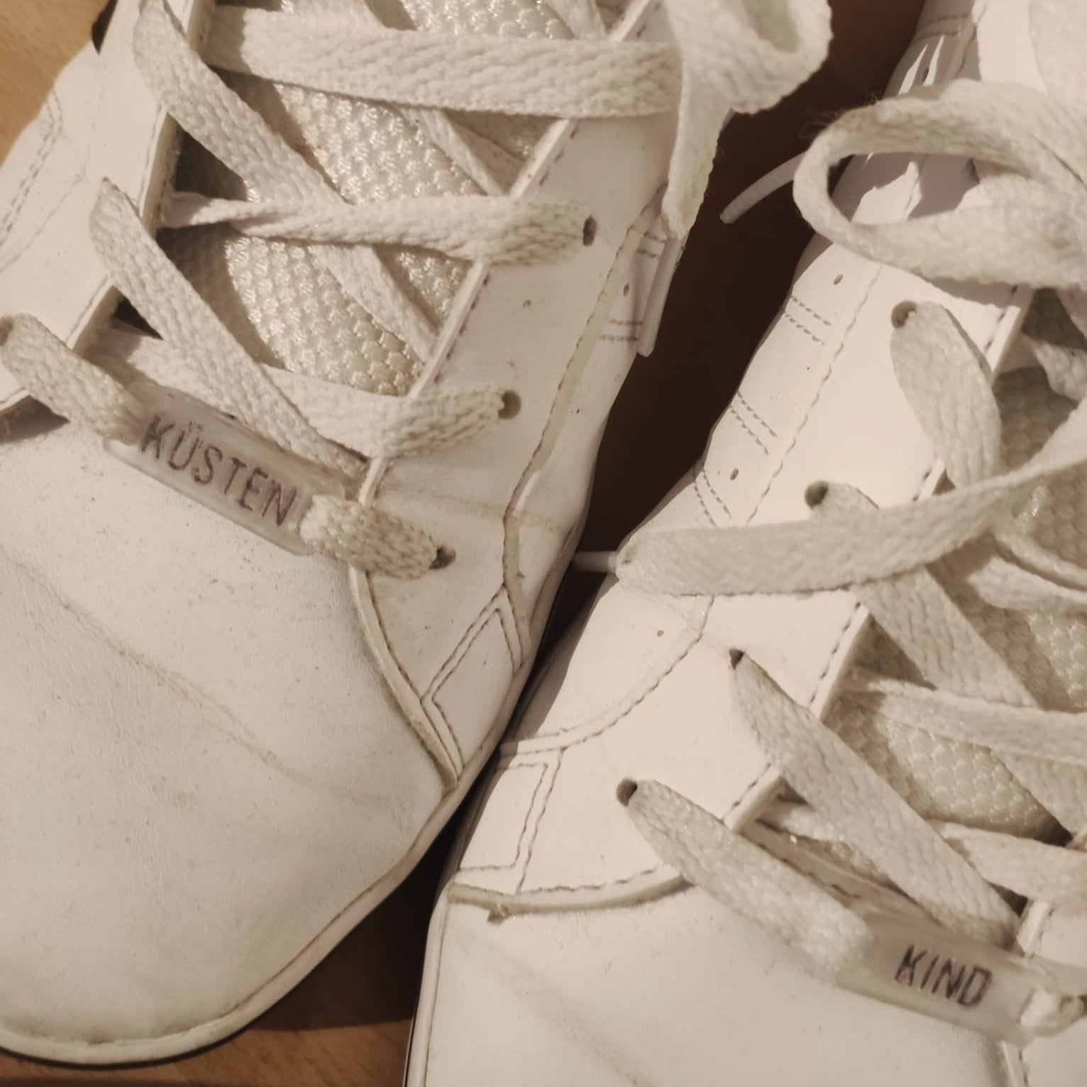 Weißes Paar Sneakers mit personalisierten Schnürsenkeln, die die Wörter 'KÜSTEN' und 'KIND' zeigen. Ideal für kreative Projekte mit der Plotter und Laser Datei von easy-sticks.