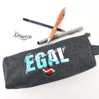 Ein graues Federmäppchen, verziert mit dem Spruch "Schnurzpiep Egal" in lebendigen Blau- und Weißtönen. Ein tolles Ergebnis der Plotterdatei von easy-sticks.
