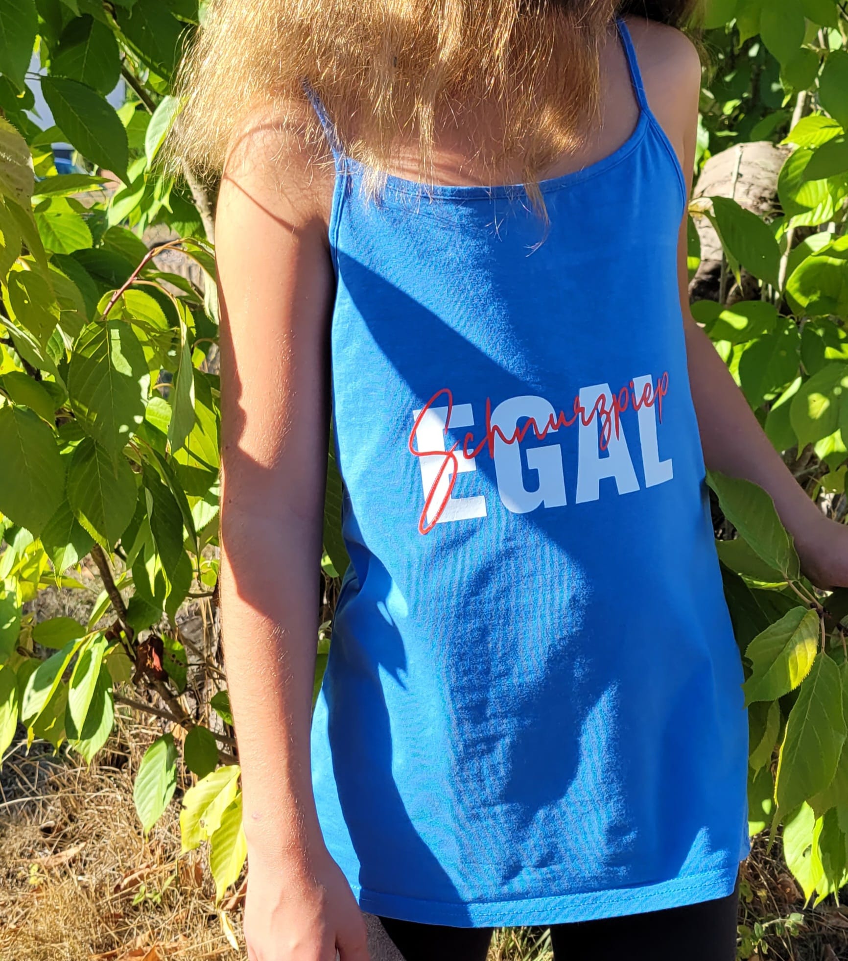 Ein blaues Trägershirt, das den Spruch "Schnurzpiep Egal" in strahlenden Farben trägt. Ein Beispiel für die vielseitige Anwendung der Plotterdatei von easy-sticks.