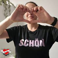 Frau in schwarzem T-Shirt mit dem Aufdruck "Schön, dass es mich gibt" und Herzform aus ihren Händen, entworfen von easy-sticks, inspiriert von der Plotterdatei.