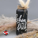 Eine elegante schwarze Vase mit der Aufschrift "Schön, dass es dich gibt" von easy-sticks. Diese inspirierende Gestaltung ist ideal für kreative Projekte mit der Plotterdatei. Die Vase wird von Trockenblumen umgeben und verleiht jedem Raum eine persönliche Note.