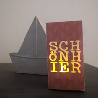 Lichtdurchlässige Deko mit der "SCHÖN HIER" Plotterdatei von easy-sticks, schematisches Design auf einer Karte, perfekt für kreative Projekte.