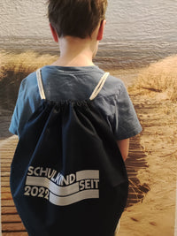 Ein Junge mit einem schwarzen Rucksack, der die Aufschrift 'SCHULKIND SEIT 2022' zeigt, designt mit der EINZIGARTIG SEIT Plotterdatei von easy-sticks.