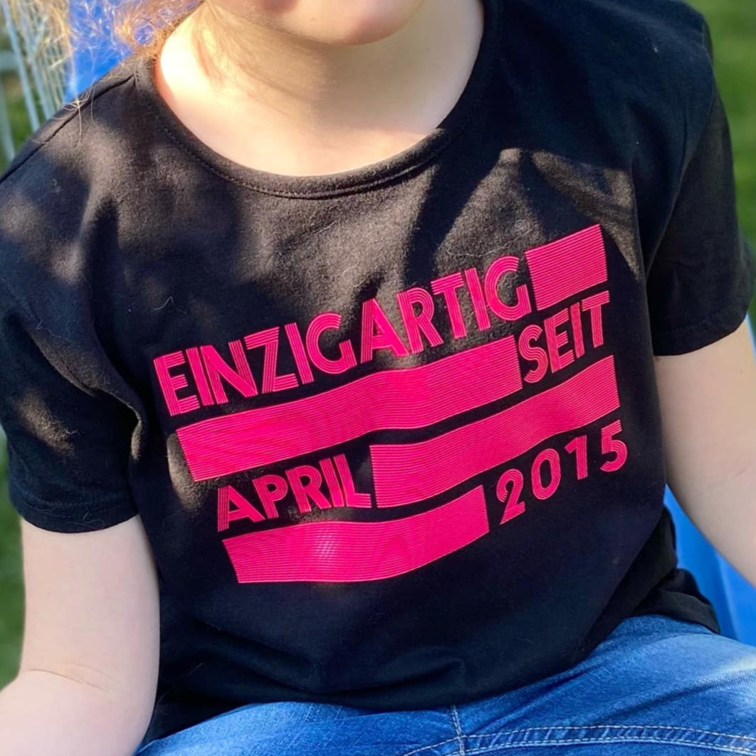 Schwarzes Kinder-T-Shirt mit dem fröhlichen Aufdruck 'EINZIGARTIG SEIT APRIL 2015', erstellt von easy-sticks, basierend auf der 'EINZIGARTIG SEIT' Plotterdatei.