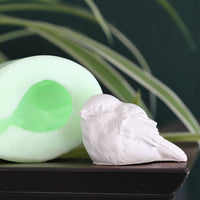 Die Silikonform "Kleiner Spatz" von Easy-Sticks präsentiert eine detailreiche, weiße Vogelfigur neben einer transparenten Silikonform, perfekt zum Modellieren von bezaubernden Spatzen für Dekorationen.