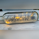 Glasflasche mit Sandschicht und leuchtenden Lichtern, verziert mit dem Schriftzug "Gartenlicht". Kreative Projekte für den Sommer mit der "Sommer und Urlaub Sprüche" Plotterdatei von easy-sticks.