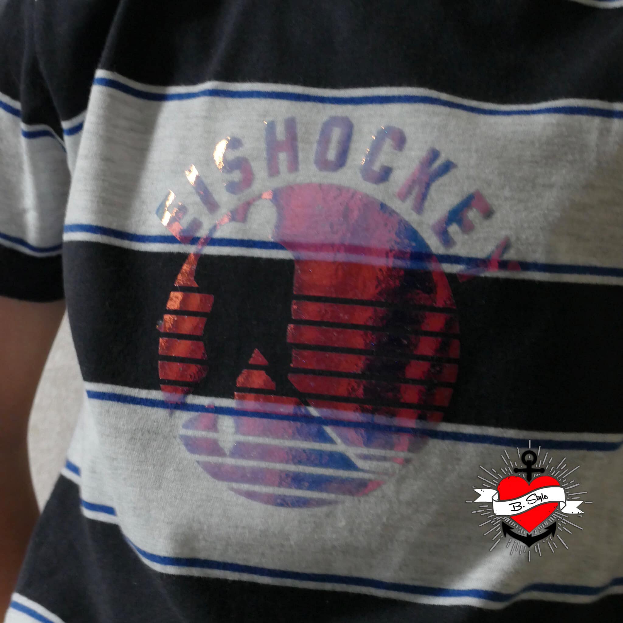 Sport 2 Abzeichen - Plotterdatei von easy-sticks auf einem gestreiften T-Shirt mit Eishockey-Design und glänzenden Akzenten.
