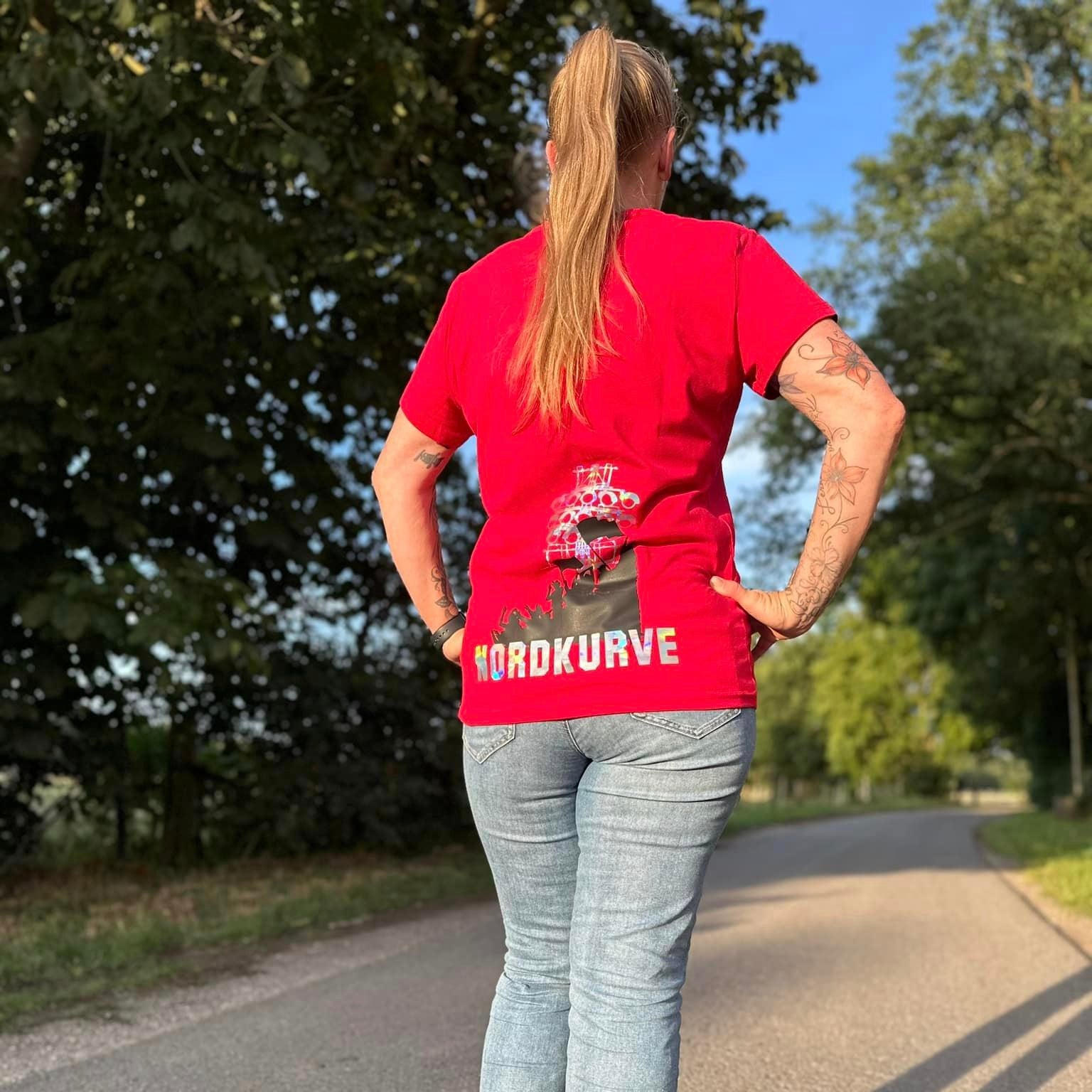 Frau zeigt Rückansicht in einem roten T-Shirt mit dem Schriftzug "Nordkurve". Perfekt für Stadionbesuche, Teil der Plotterdatei "Stadionzeit" von easy-sticks.