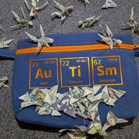 Bunte Tasche mit chemischen Symbolen aus dem Periodensystem von easy-sticks, umgeben von kunstvoll gefalteten Papierfliegern, ein kreatives DIY-Modell.