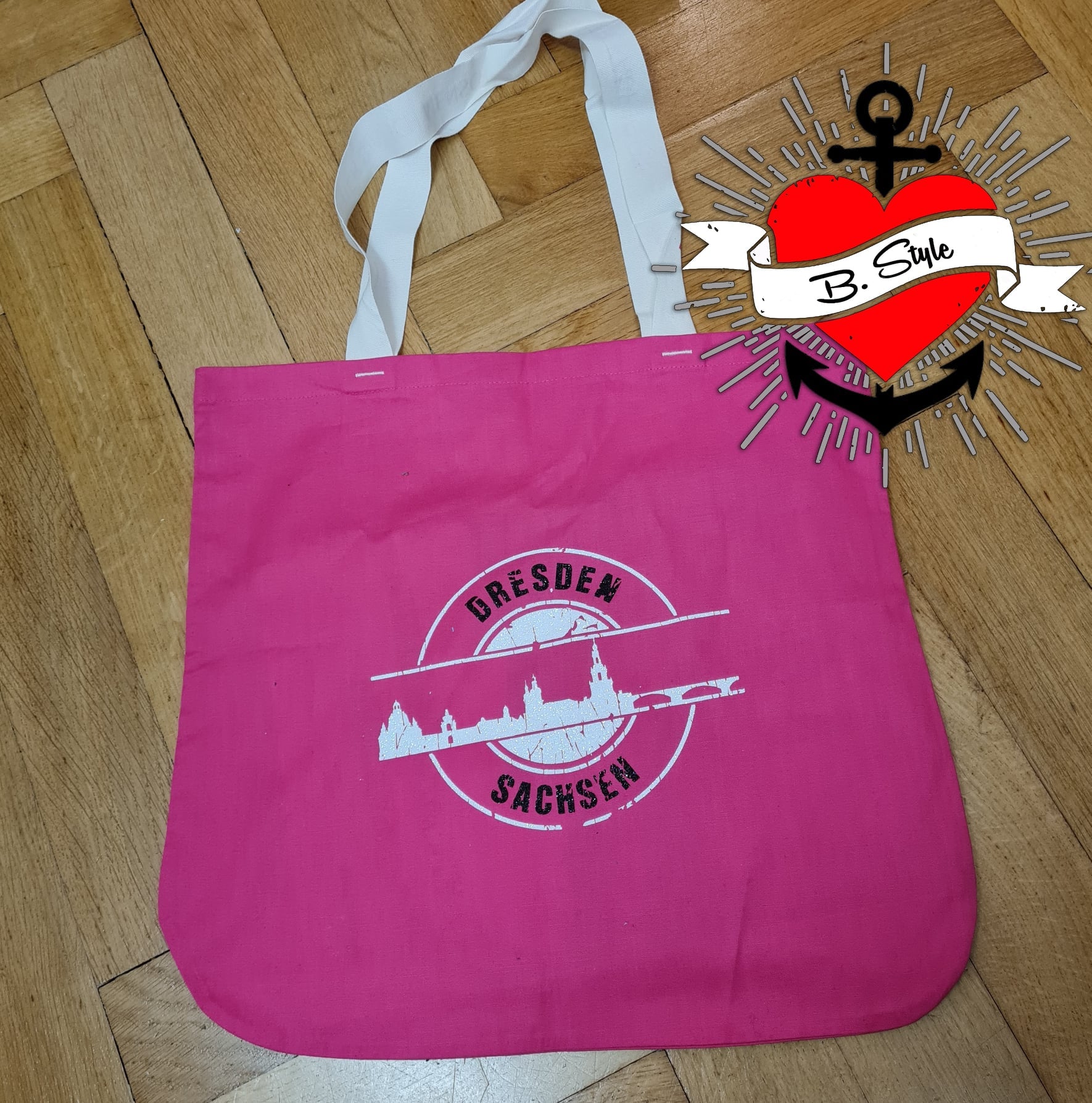 Eine pinke Tragetasche mit dem aufgedruckten Design "Stempel Skyline Dresden" von easy-sticks, das als Plotterdatei für kreative Projekte dient.