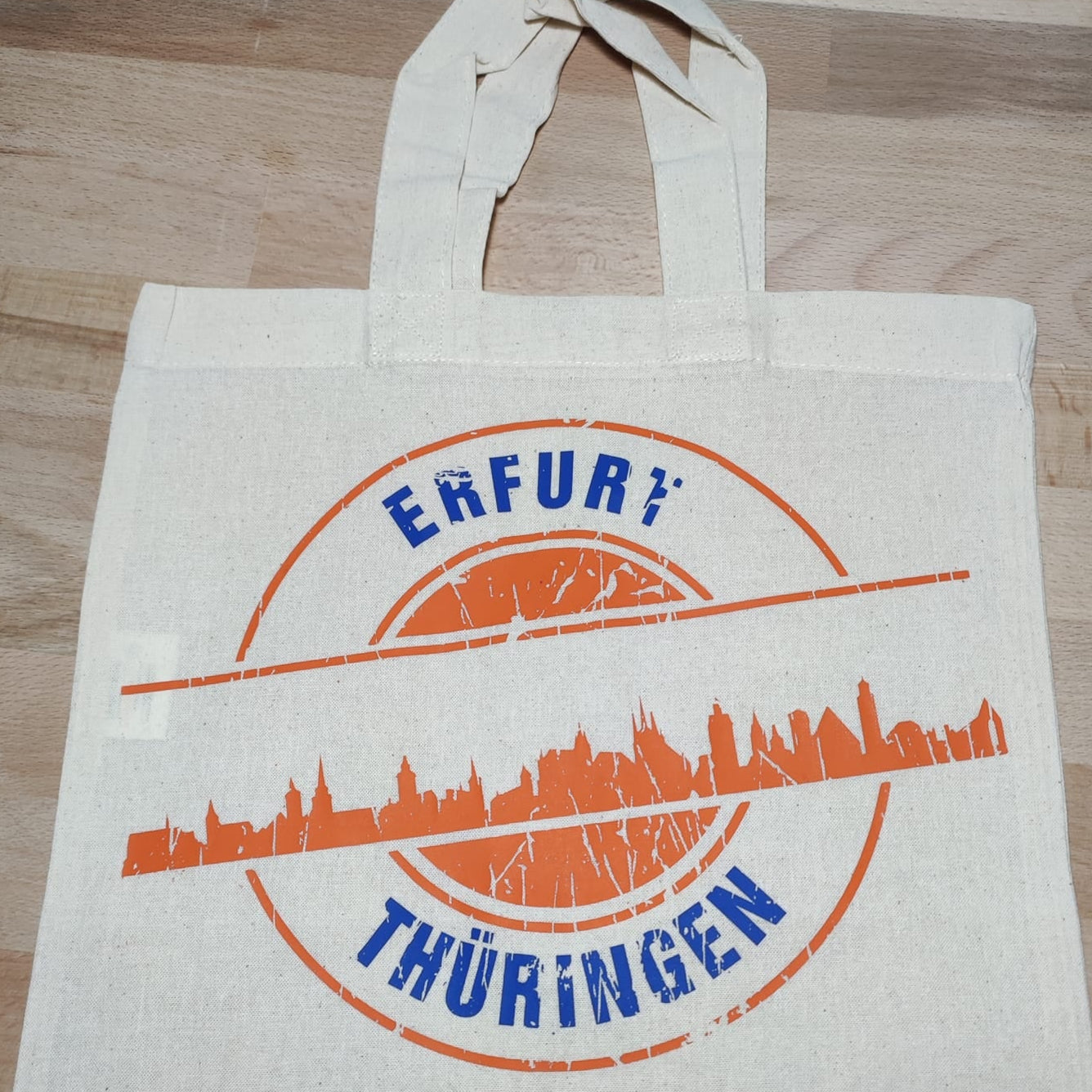 Helle Baumwolltasche mit orangefarbenem Skyline-Motiv von Erfurt und dem Text "Erfurt Thüringen". Perfekt für DIY-Projekte mit der "Stempel Skyline Erfurt" Plotterdatei von easy-sticks.