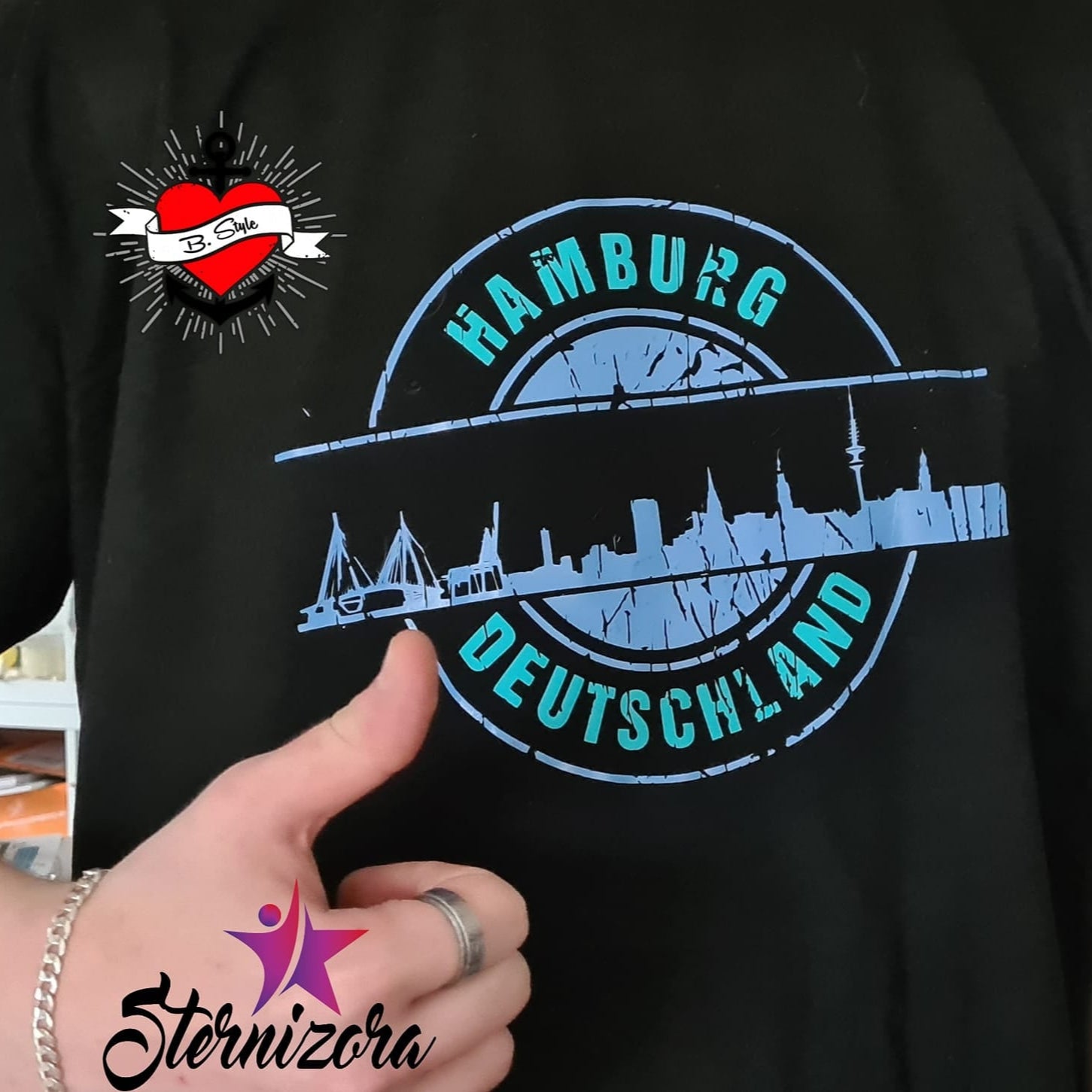 Ein schwarz getragenes T-Shirt mit der markanten Hamburg Skyline, gestaltet mit der "Stempel Skyline Hamburg" Plotterdatei von easy-sticks, ideal für kreative Ausdrucksformen.