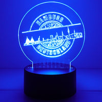 Eine leuchtende Acryl-Lampe mit der Skyline von Hamburg, die die "Stempel Skyline Hamburg" Plotterdatei von easy-sticks zeigt, ideal für kreative Projekte.