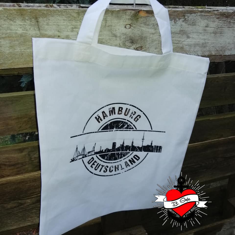 Eine weiße Tragetasche, die die stilisierte Skyline von Hamburg zeigt, erstellt mit der "Stempel Skyline Hamburg" Plotterdatei von easy-sticks, großartig für individuelle Designs.