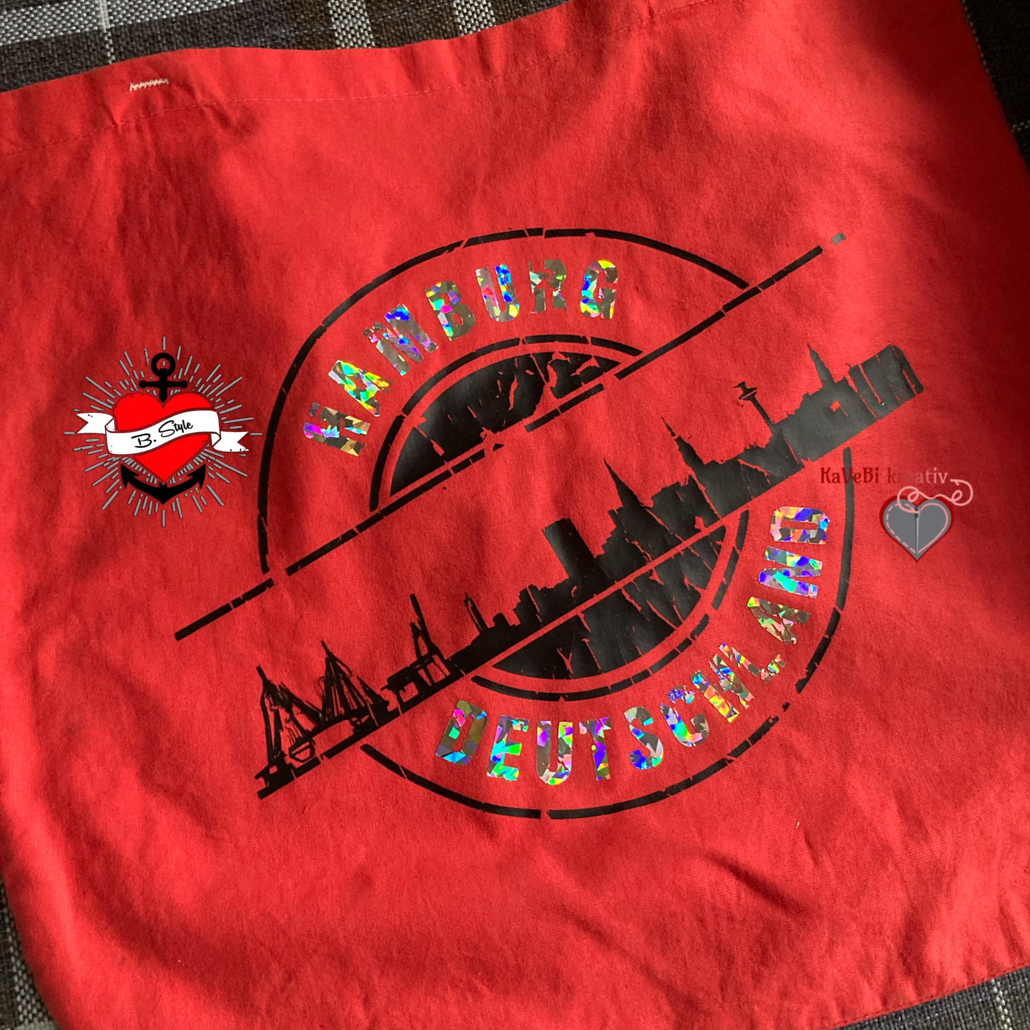 Eine rote Tasche, verziert mit der Hamburg Skyline, entworfen mit der "Stempel Skyline Hamburg" Plotterdatei von easy-sticks, ideal für kreative Bastelarbeiten.