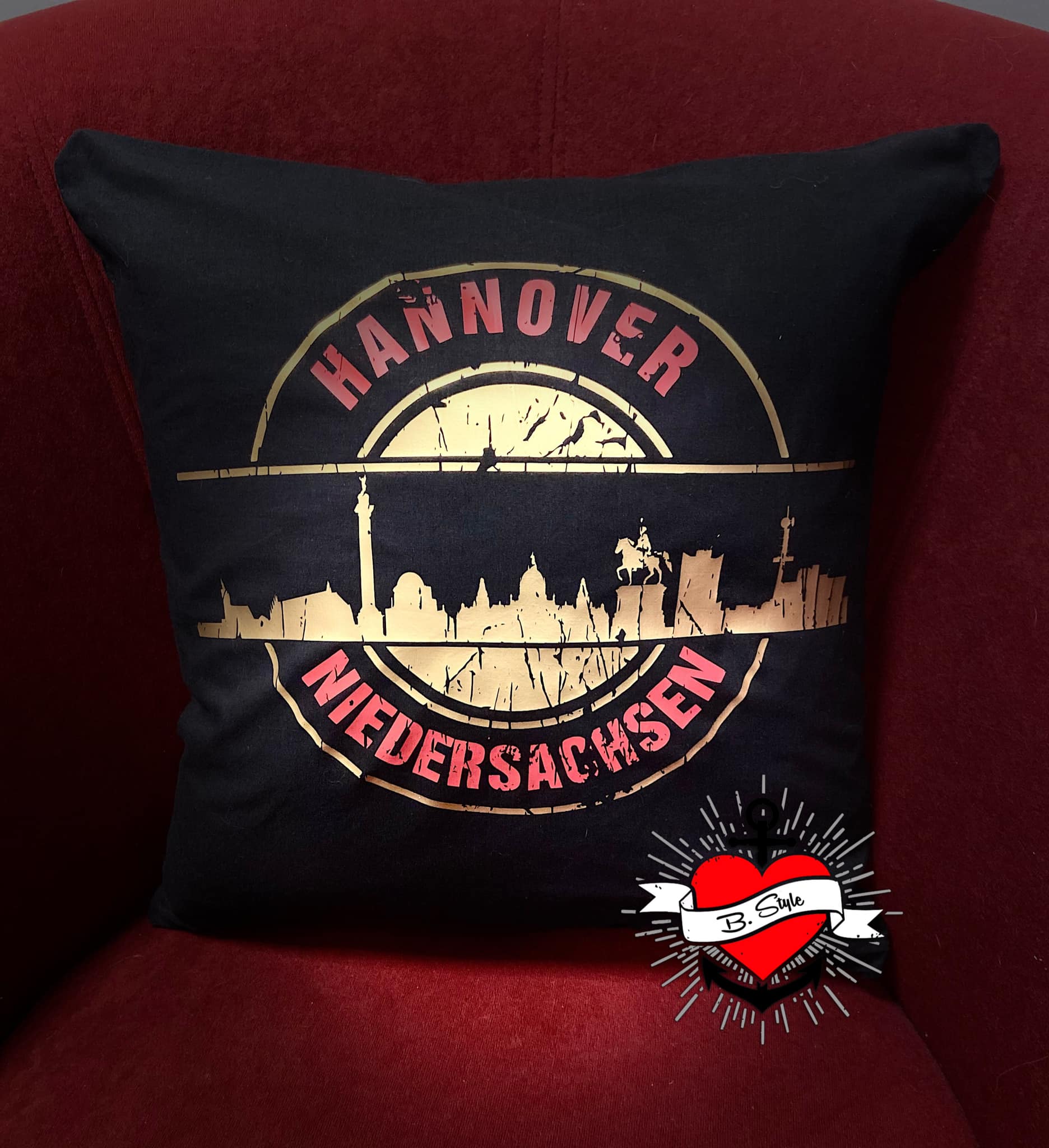 Dekoratives Kissen mit dem Aufdruck "Stempel Skyline Hannover" von easy-sticks. Präsentiert die Skyline von Hannover in goldener Schrift, ideal für kreative Projekte mit der Plotterdatei.