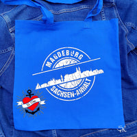 Eine blaue Tragetasche mit dem stylischen Motiv "Stempel Skyline Magdeburg" von easy-sticks, basierend auf der vielseitigen Plotterdatei für DIY-Projekte.