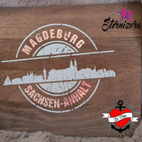 Stempel Skyline Magdeburg von easy-sticks – Die Plotterdatei präsentiert die Silhouette von Magdeburg auf einem Holzuntergrund, ergänzt durch die Aufschrift "Sachsen-Anhalt". Perfekt für kreative Bastelarbeiten.