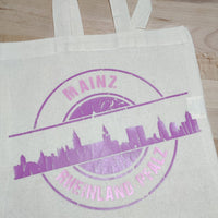 Die Stempel Skyline Mainz Plotterdatei von easy-sticks auf einer Baumwolltasche in lila, ideal für kreative DIY-Projekte.