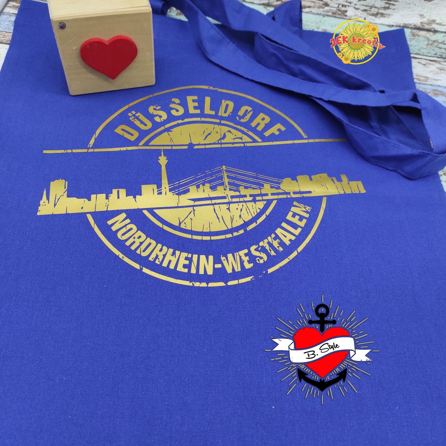 Stempel Skyline München Plotterdatei von easy-sticks: Ein blauer Stoffbeutel mit der Skyline von Düsseldorf, verziert durch goldene Akzente, perfekt für DIY-Bastelarbeiten.