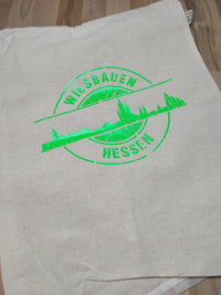 Die Skyline Wiesbaden Plotterdatei von easy-sticks ist in dieser minimalistischen Baumwolltasche abgebildet, mit dem auffälligen Design 'WIESBADEN HESSEN' in leuchtenden Farben.