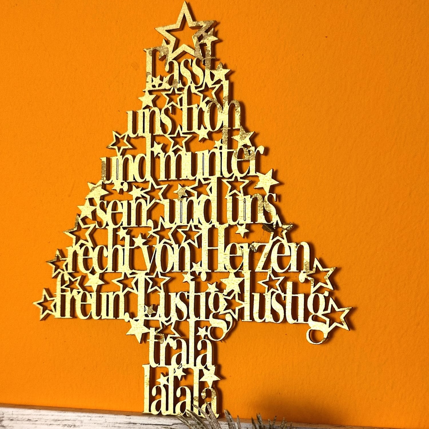 Ein kunstvoller Tannenbaum aus Holz, der die Worte "Lasst uns froh und munter sein, und uns recht von Herzen freun. Lustig, lustig, trala lalala" zeigt. Ideal für kreative Weihnachtsprojekte von easy-sticks.