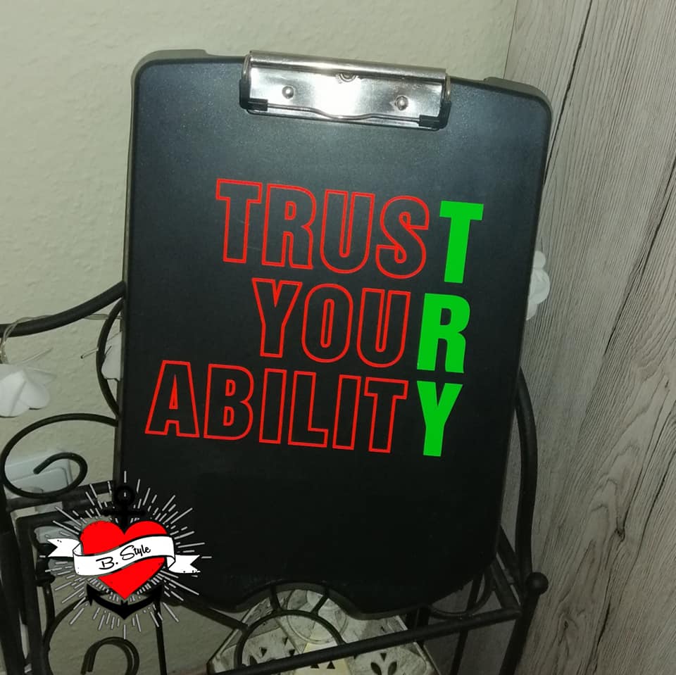 Schwarzes Clipboard mit dem auffälligen Text 'TRUST YOUR ABILITY' in verschiedenen Farben von easy-sticks, angefertigt mit der Plotterdatei.