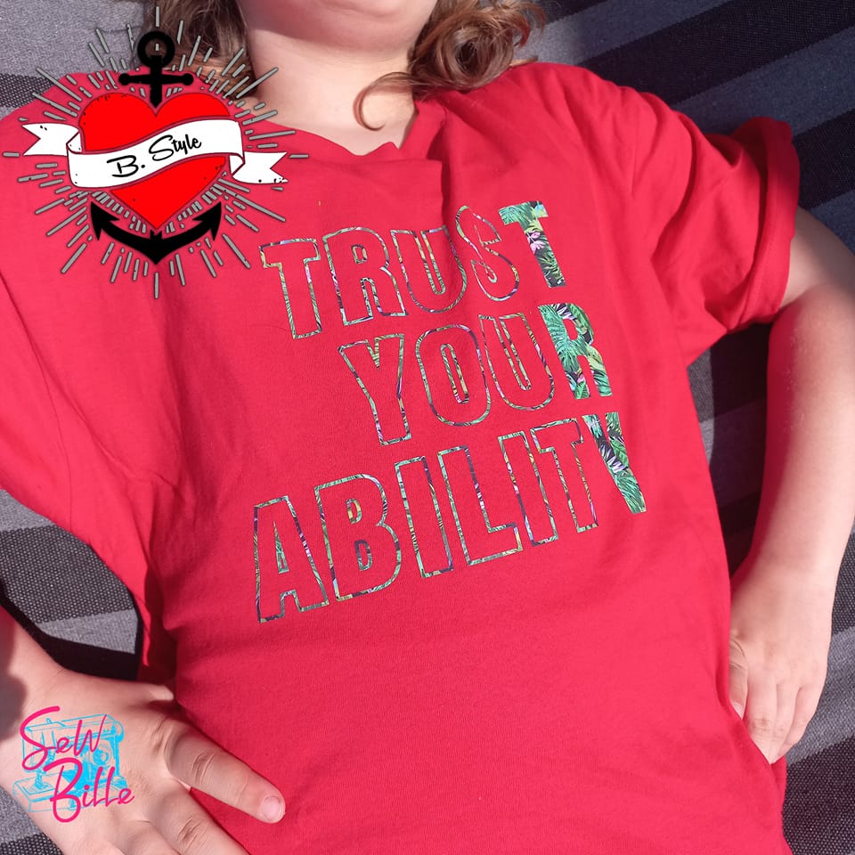 Kind trägt ein rotes T-Shirt mit dem Spruch "TRUST YOUR ABILITY" von easy-sticks, ideal für inspirierende Bastelprojekte und kreative Modegestaltungen. Das bunte Design bringt Freude und Motivation.