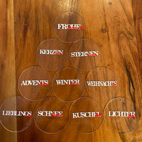 Transparente Anhänger mit weihnachtlichen Begriffen wie 'Frohe Weihnachten' und 'Kerzen' auf Holzuntergrund. Ein kreatives Geschenk von Easy-Sticks aus der Weihnachtswörter Duo Plotter Datei.
