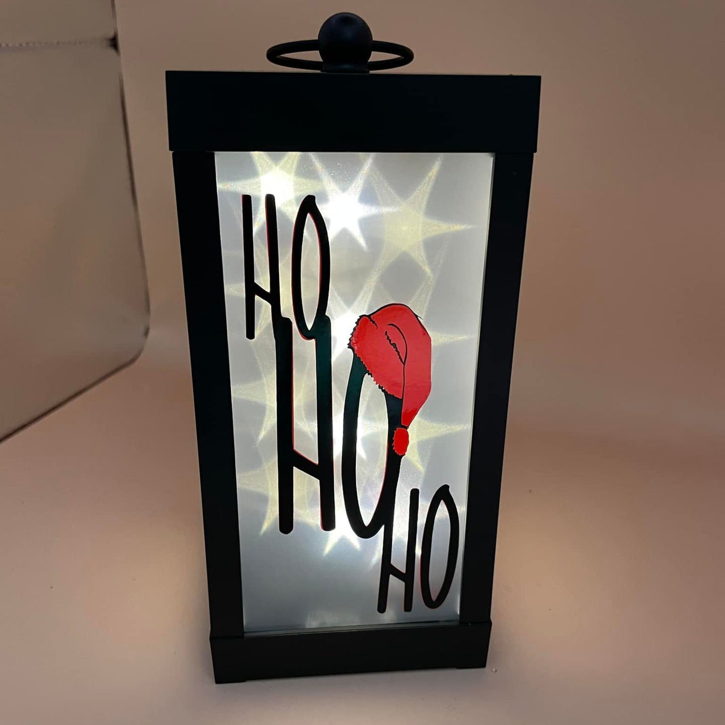 Moderne Tischlaterne mit dem Schriftzug 'HO HO HO', beleuchtet und kreativ gestaltet, basierend auf der Plotterdatei von Easy-Sticks: 'Oh du fröhliche Hohoho Tannenbaum Weihnachten Weihnachtsmützen'.