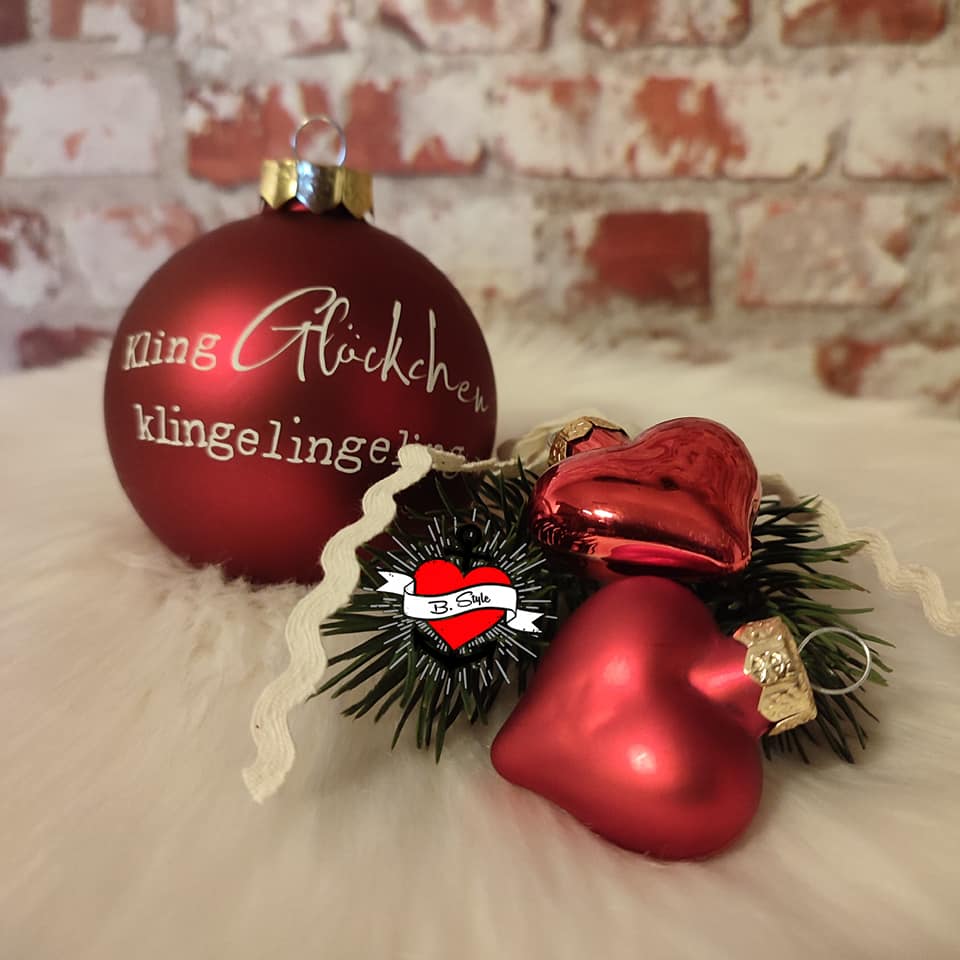 Rote Christbaumkugel mit der Aufschrift 'Kling Glückchen' zusammen mit roten Herzen und Tannenspitzen auf einem flauschigen Untergrund, von easy-sticks, Teil der Weihnachtsgrüße 2 Plotterdatei und PDF für Kerzengestaltung.