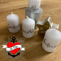 Verschiedene Kerzen mit ganzheitlicher Beschriftung für die Adventszeit, dekorative Sternenanhänger auf einem Holztisch, erhältlich von easy-sticks, aus der Weihnachtsgrüße 2 Plotterdatei und PDF für Kerzengestaltung.
