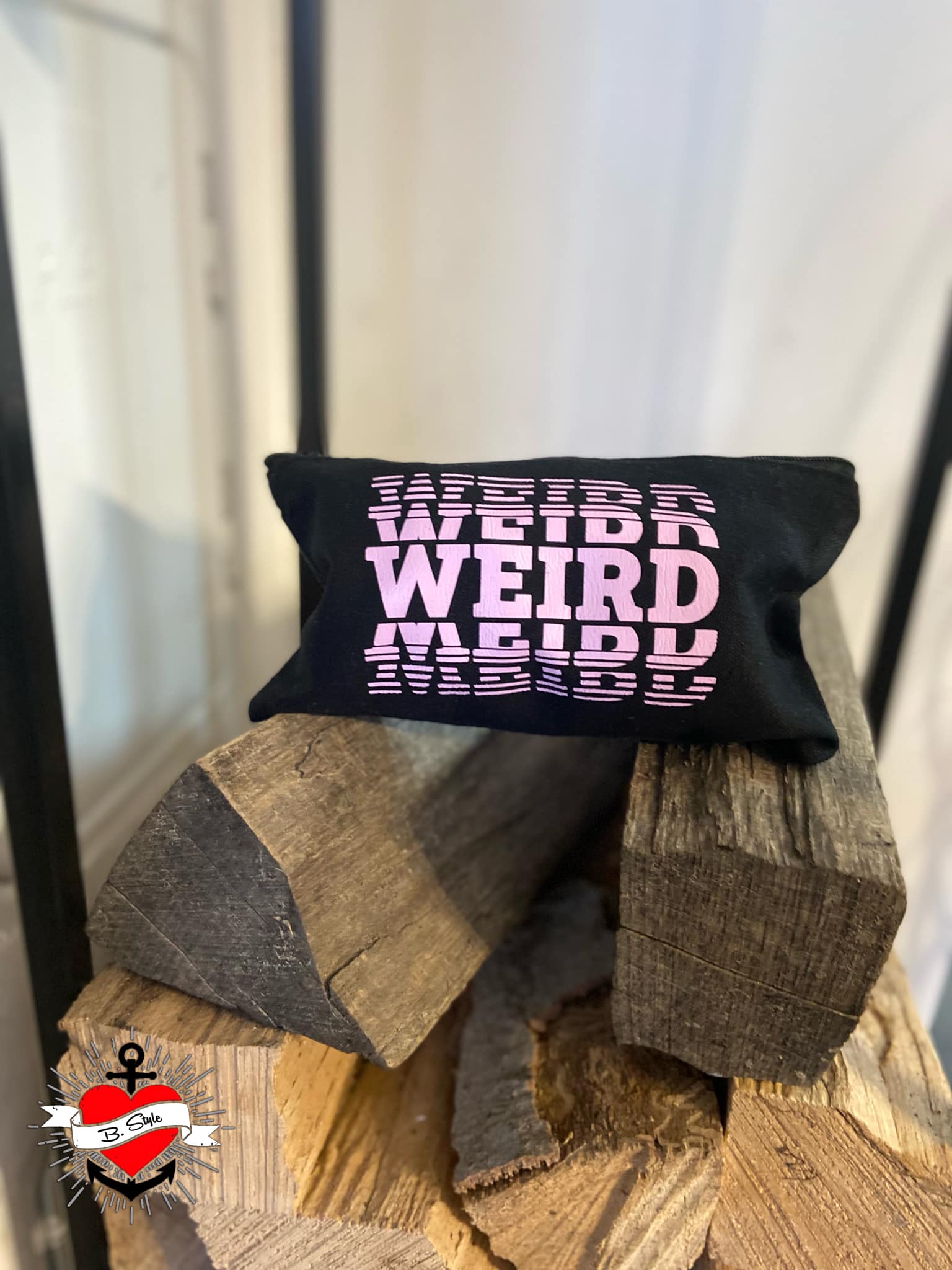 Ein schwarzes Kissen mit dem Schriftzug "WEIRD" in Pink, chillig auf einem Stapel Holz platziert, inspiriert von der kreativen "Weird" Plotterdatei von easy-sticks.