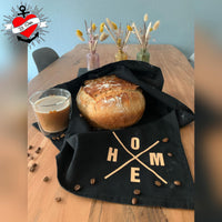 Ein frisch gebackenes Brot auf einem Tisch, umgeben von einer schwarzen Tischdecke mit dem Schriftzug "X Worte", gestaltet von easy-sticks.