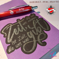Kreative Bastelarbeit mit der Plotterdatei "Zeit, die wir uns nehmen, ist die Zeit, die uns was gibt." von easy-sticks. Das Bild zeigt elegant geschnittene Schrift auf lila Papier, ideal für DIY-Projekte.