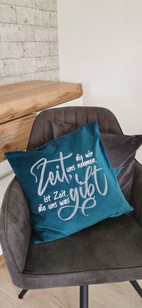Teppichkissen in Türkis mit der Aufschrift "Zeit, die wir uns nehmen, ist die Zeit, die uns was gibt." von easy-sticks, ein stilvolles Accessoire für dein Zuhause.