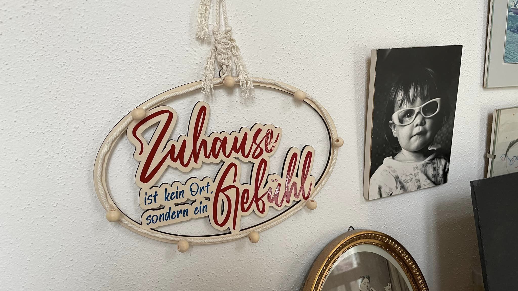 Ein kreatives Wanddekor mit dem Text 'Zuhause ist kein Ort, sondern ein Gefühl' von easy-sticks, umgeben von nostalgischen Bildern und einer gemütlichen Atmosphäre.