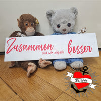Niedliche Plüschtiere posieren mit einem Holzschild, auf dem die Worte "Zusammen sind wir einfach besser" stehen, entworfen von easy-sticks.