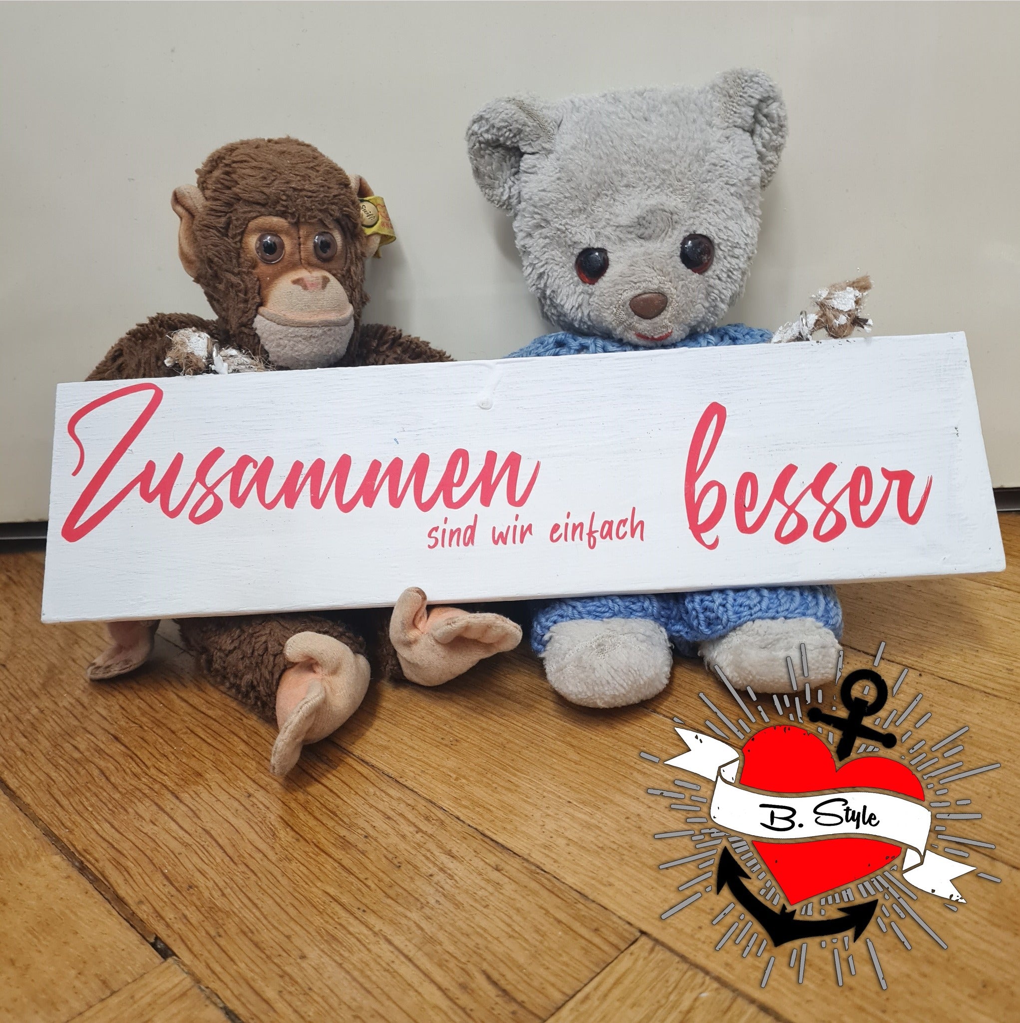 Niedliche Plüschtiere posieren mit einem Holzschild, auf dem die Worte "Zusammen sind wir einfach besser" stehen, entworfen von easy-sticks.