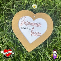 Herzförmiges Holzschild mit der Aufschrift "Zusammen sind wir einfach besser" im Freien, gestaltet mit der Plotterdatei von easy-sticks.