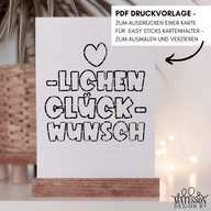 Stilvolle HERZLICHEN GLÜCKWUNSCH Karte zum Downloaden und Ausdrucken von Easy-Sticks, präsentiert auf einem modernen Holzständer mit dekorativem Hintergrund, ideal für persönliche Glückwünsche.