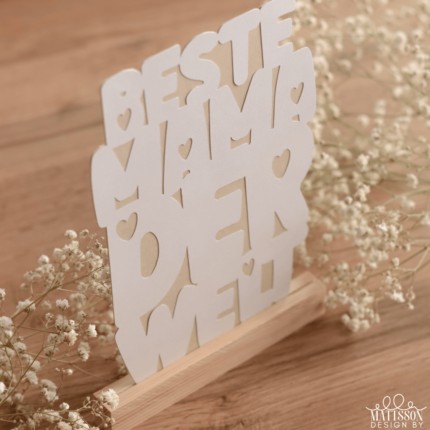 Einzigartige Deko für die beste Mama: Plotterdatei von easy-sticks mit dem Schriftzug 'BESTE MAMA DER WELT', umgeben von zarten Blumen.