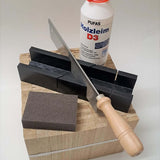 Easy-Sticks 4.0 Starter Set von Easy-Sticks präsentiert mit Säge, Holzleim und Schleifschwamm auf einem robusten Holzblock. Perfekt für Modelle und Bastelarbeiten.