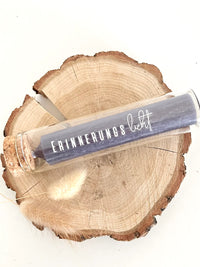Rub On UV Sticker randlos von easy-sticks, präsentiert in einem eleganten Glasröhrchen mit dem Schriftzug 'ERINNERUNGSlicht' auf einem natürlichen Holzuntergrund.
