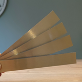 Eine Hand hält vier goldene Easy-Sticks von Easy-Sticks, 16 cm lang. Perfekt für vielfältige Bastelideen und kreative Anwendungen, um jeden Raum zu verschönern.