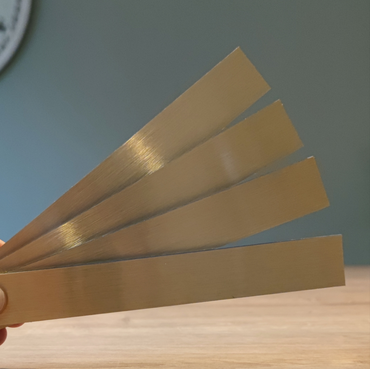 Eine Hand hält vier goldene Easy-Sticks von Easy-Sticks, 16 cm lang. Perfekt für vielfältige Bastelideen und kreative Anwendungen, um jeden Raum zu verschönern.