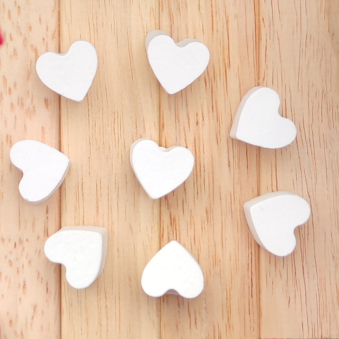 Naheinstellung von 15 Mini Herzen aus Silikon von easy-sticks, die auf einer Holzoberfläche liegen, ideal für kreative Bastelprojekte und personalisierte Dekorationen.