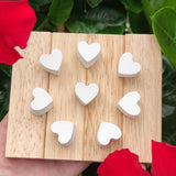 15 Mini Herzen aus Silikon von easy-sticks, auf einem Holzbrett platziert, umgeben von Blumen, um die Vielseitigkeit und Kreativität bei DIY-Projekten zu zeigen.
